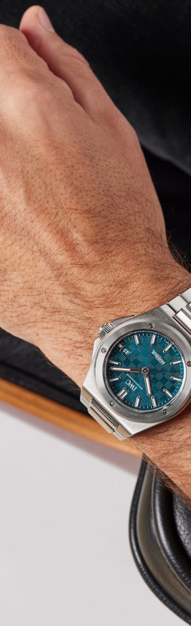 Close-up of a wrist wearing a stainless steel watch with a blue dial, highlighting IWC's durable metal bracelet design.