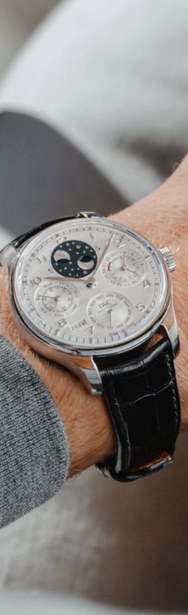 Gros plan d’un poignet d’homme portant un calendrier perpétuel IWC avec un bracelet en cuir noir.