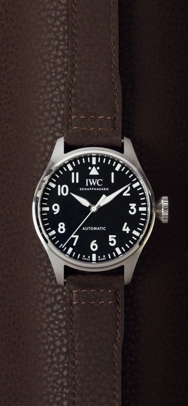 IWC Pilot's Watch with black dial and brown leather strap on a brown leather background