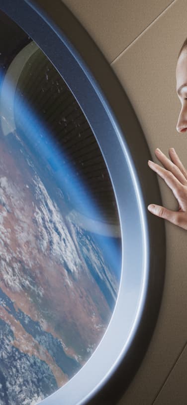 A female astronaut looking through the window of a space station at the Earth’s surface.