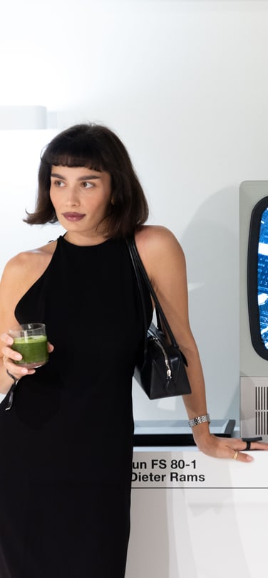 Person posing next to a vintage Braun FS 80-1 television designed by Dieter Rams, displaying an IWC watch, at the IWC Ingenieur Residency.