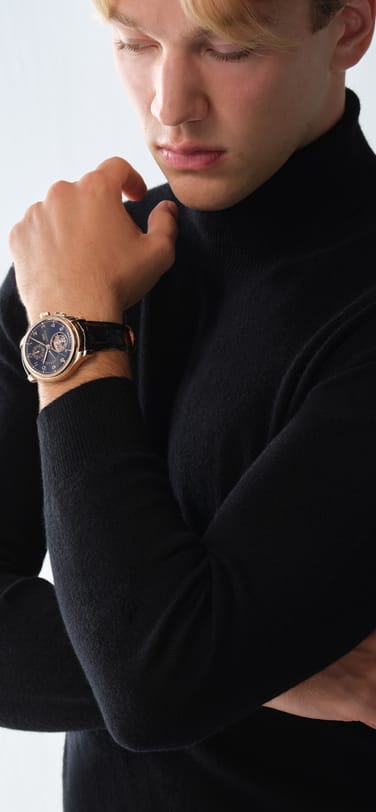 IWC Portugieser Tourbillon Chronograph with black dial, gold case and black leather straps on a man's wrist