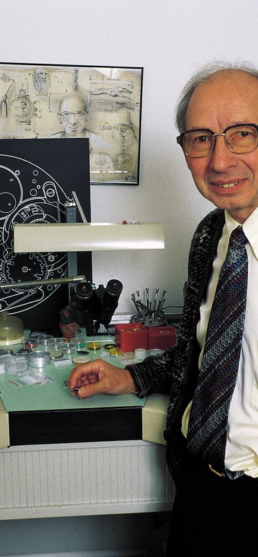 Kurt Klaus at his workbench at IWC Schaffhausen, with a technical movement schematic displayed behind him