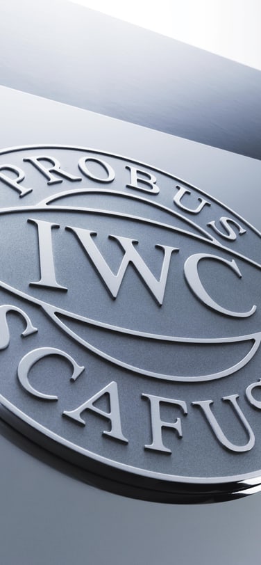 The IWC logo with the motto “Probus Scafusia” on a light grey background