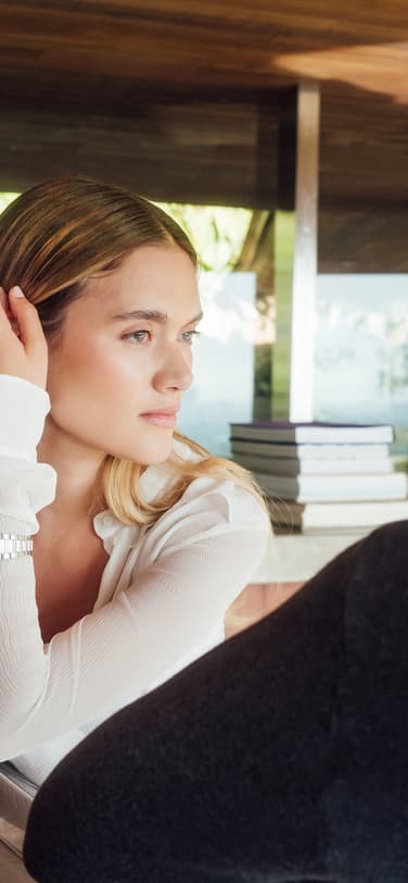 An elegant woman, wearing an Ingenieur watch with diamonds and white blouse, in a thoughtful conversation with a man within a bright, contemporary interior.
