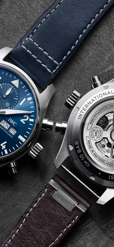 Zwei IWC Schaffhausen Pilot's Watches liegen flach. Die linke hat ein blaues Zifferblatt und ein Lederarmband, während die rechte umgedreht ist, um ihren transparenten Gehäuseboden und ihr mechanisches Uhrwerk zu zeigen, mit mehreren Armbändern an der Seite.