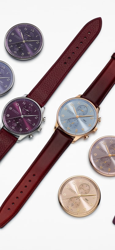 Multiple IWC watch dials and straps in various colors lying on a white surface