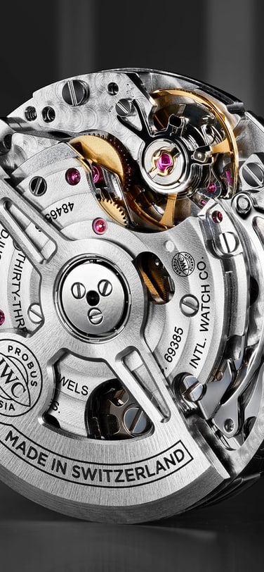 Eine Nahaufnahme, Dreiviertel-Ansicht, eines IWC Schaffhausen Automatik-Uhrwerks, das die komplexen Zahnräder, Lagersteine und den halbmondförmigen Rotor präsentiert.
