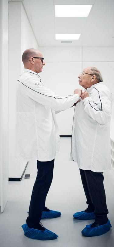Two watchmakers wearing anti-static watchmakers’ coats