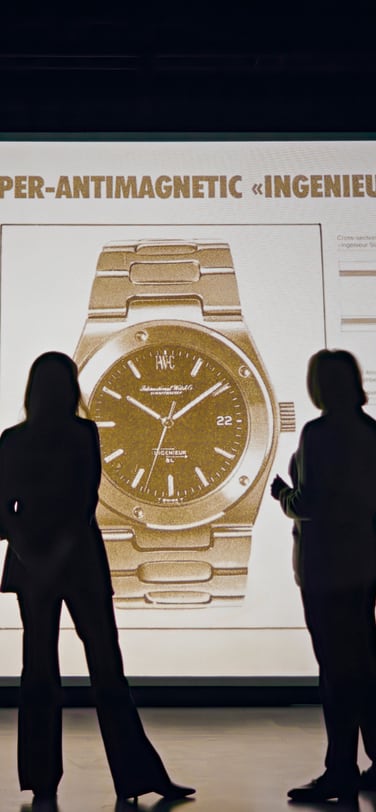 Two women, Evelyne and Alexia Genta, standing in front of a projection of Gerald Genta’s Ingenieur SL