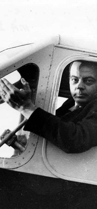 Antoine de Saint-Exupéry, the famous aviator, seated in the pilot's seat of an airplane.