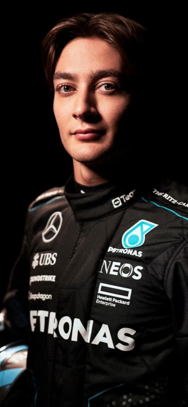 Grand Prix-winner and IWC brand ambassador George Russell in black uniform with brand logos holding helmet