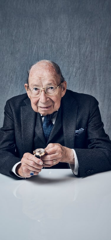 身著灰色西裝、手持萬年曆腕錶的年長紳士