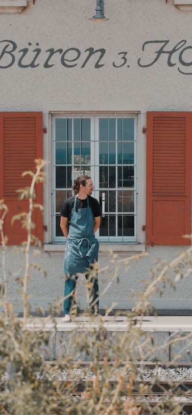 Ceramicist Laurin Schaub standing in front of the train station Büren zum Hof, where his pottery workshop is located