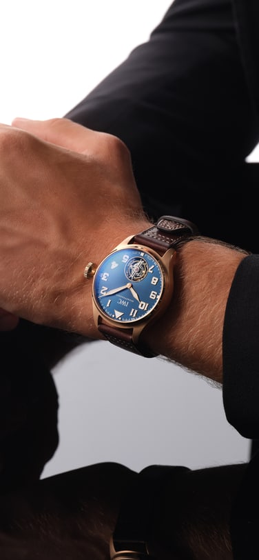 IW329502 with blue dial, gold case and brown leather strap on a man's wrist resting on a table