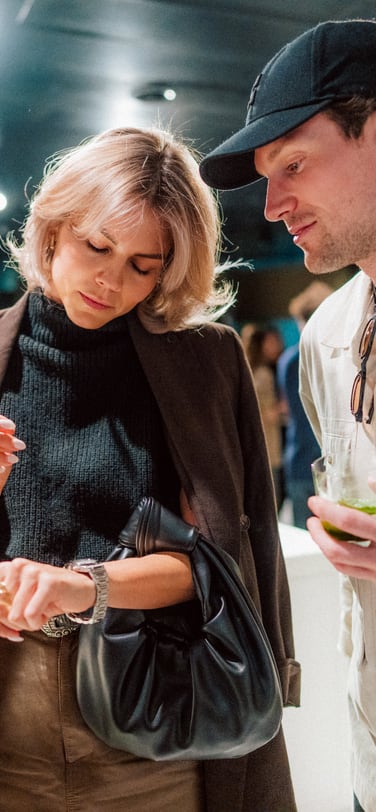 Woman checking the time on an IWC Ingenieur watch while a man looks on, at the IWC Ingenieur Residency event.