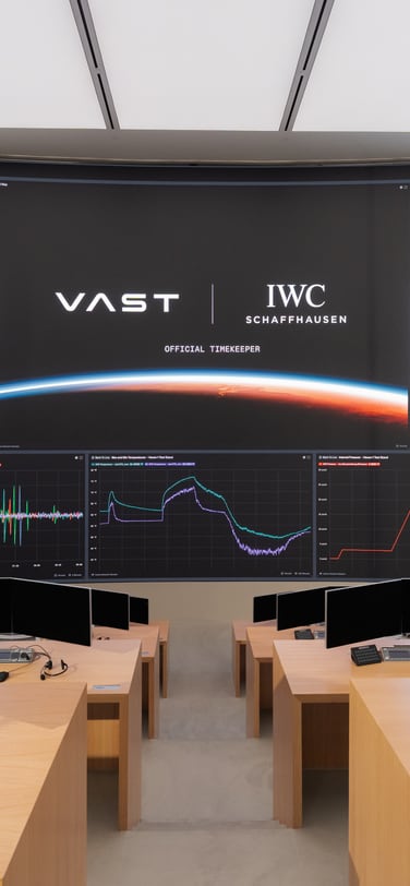 a room with a big screen showing IWC and VAST logos