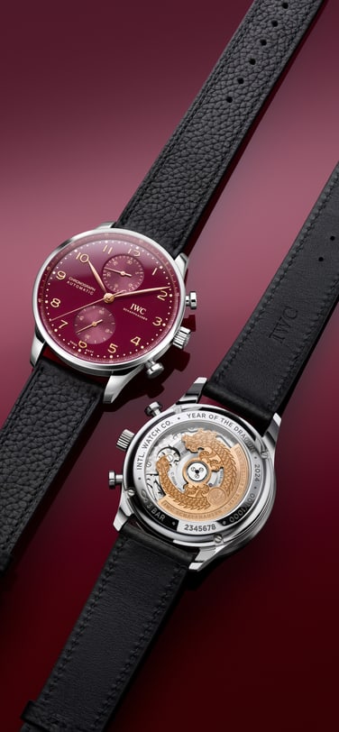 Two Portugieser Chronograph Year of the Dragon watches with Red dial, Stainless steel Case and Black calfskin strap on red surface.