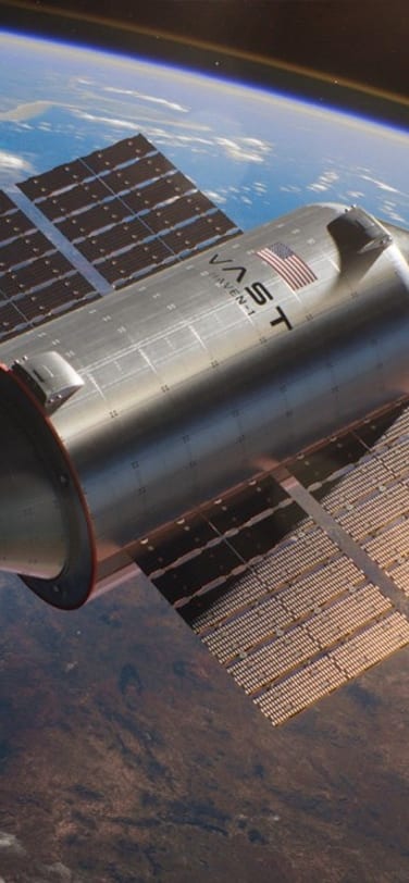 A spaceship with VAST written on it photographed in space with earth in the background.