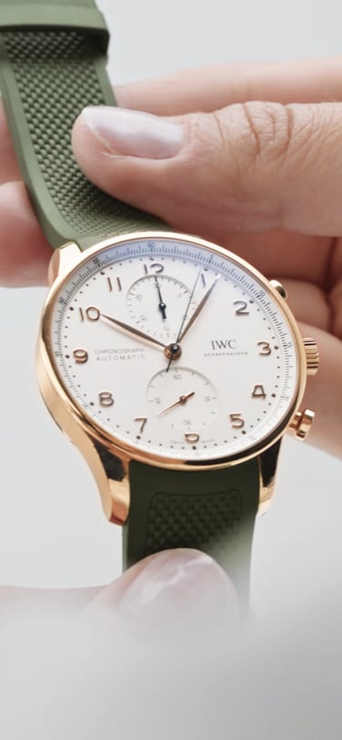 IWC Portugieser watch with white dial and green rubber strap is being held by two hands