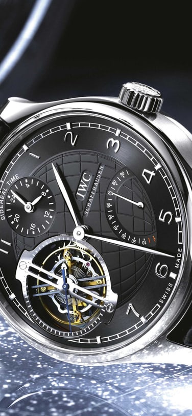 IWC Portugieser Sidérale Scafusia avec un cadran noir, un boîtier un platine et un bracelet en alligator noir sur une surface bleue.