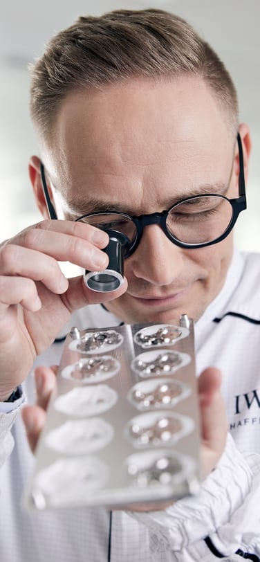 Watchmaker in IWC white robe examining the watch movement