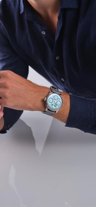 Man with blue shirt wearing Portugieser Perpetual Calendar watch with light blue dial and blue leather strap oh his wrist
