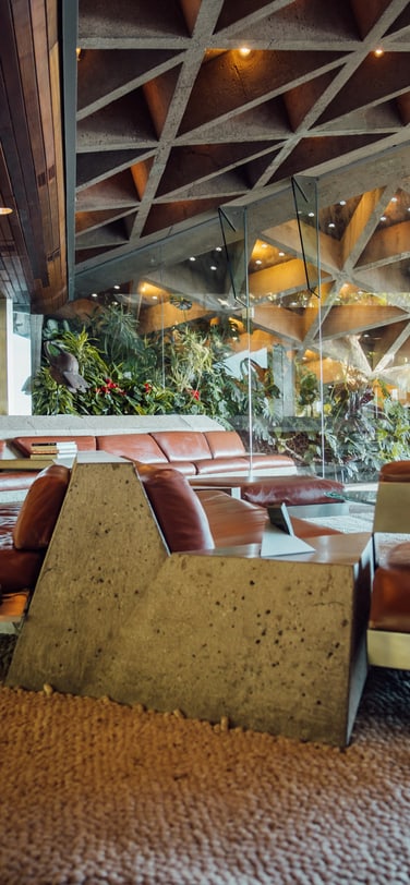 The modernist interior of the Goldstein Residence’s living room featuring a large brown leather couch and a geometric ceiling