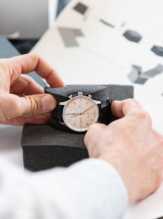 Hands placing IWC watch in shipping kit.