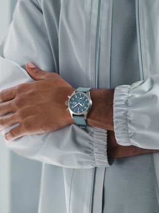 Wrist shot of male hand wearing the IWC Pilot’s Watch Chronograph 41 with light blue dial and strap.