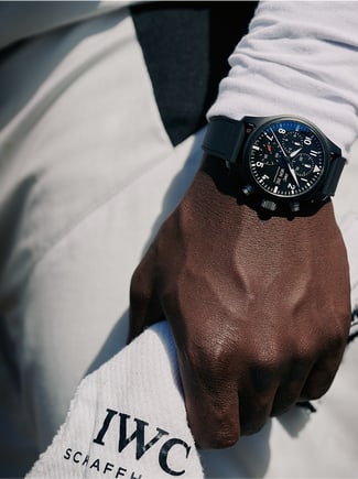 A man dressed in white racing suit with a black IWC watch on the wrist
