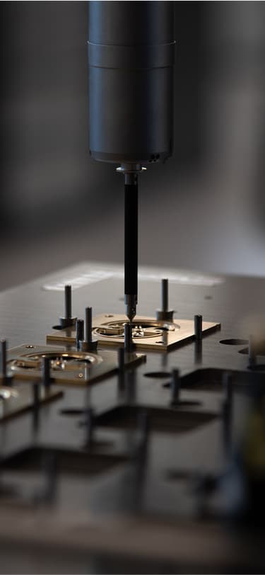 A precision machine tool works on small watch components, highlighting the role of automation in high-end watch manufacturing.