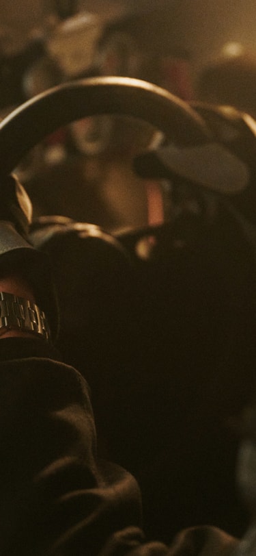 Closeup image of a man's wrist inside racing car, wearing the Ingenieur Automatic 40 green dial.