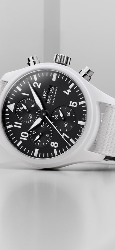 IWC Portugieser Chronographe avec un cadran noir, un boîtier en or et un bracelet en caoutchouc noir sur un fond noir