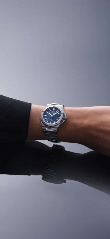 Close-up of a wrist in a dark sleeve wearing an IWC watch with a blue dial