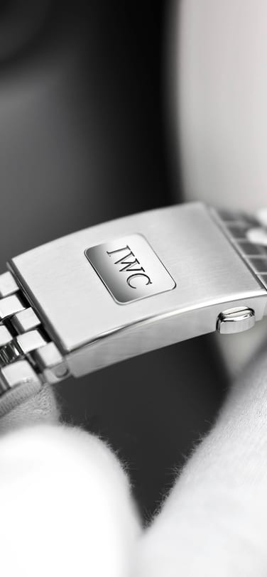 Hands wearing white gloves holding an IWC watch clasp