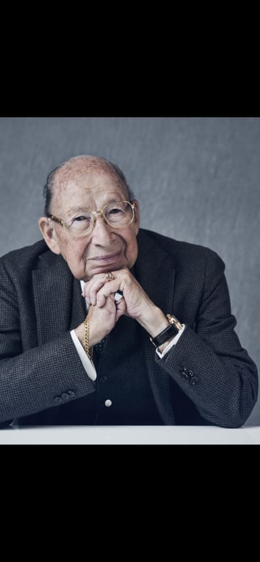90-year-old watchmaker Kurt Klaus seated in front of a gray background