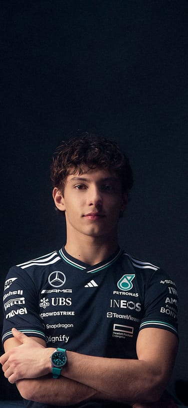 Mercedes Driver Kimi Antonelli in front of a silver racing car wearing a watch with a PETRONAS green strap.