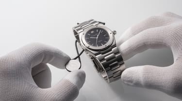 Hands in white gloves holding the Ingenieur SL watch with IWC.Curated. certification.