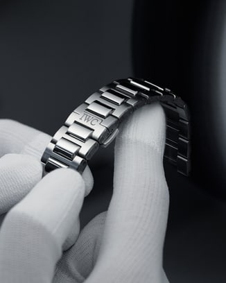 Finger, die ein Edelstahlarmband mit H-förmigen Gliedern berühren