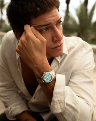 Man wearing an IWC watch with a mint turquoise dial on a stainless steel bracelet.