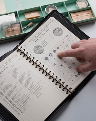 Hand pointing at IWC watch information catalogue book.