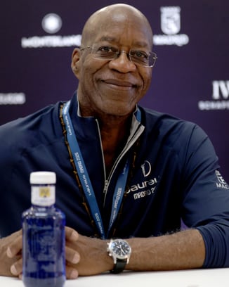 Zwei Männer gehen und unterhalten sich auf einem Golfplatz und lachen, im Hintergrund ein IWC-Banner.