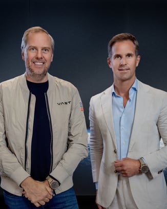 two men posing in front of a background showing an image of earth in space