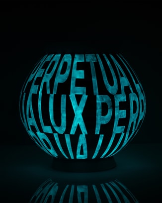 A dark ceramic moon jar illuminated by the words "LUX PERPETUA" glowing brightly in blue Ceralume