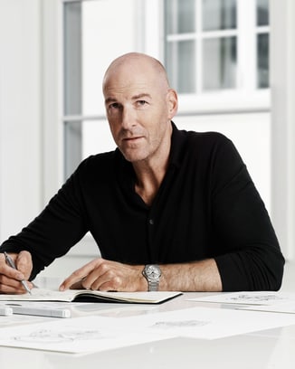 Portrait image of a man dressed in a black shirt and seated at a white table