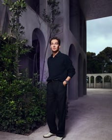 George Rusell standing infront of a building and foliage modelling Pilot's Watch Chronograph 41 Mercedes-AMG Petronas Formula One™ Team watch and Adidas sneakers.